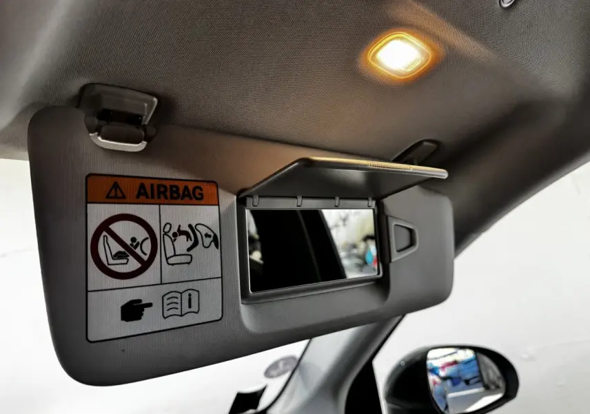 Détail du pare-soleil intérieur avec miroir et avertissement airbag dans un Mercedes GLC gris foncé, vue côté gauche.