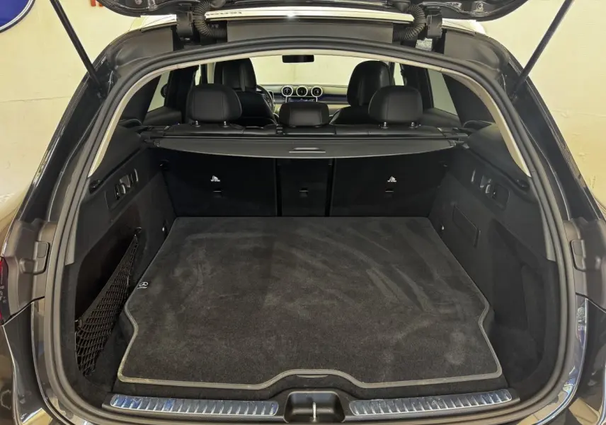 Coffre ouvert vu de l'arrière d'un Mercedes GLC 300 E Business Line gris foncé, avec tapis de coffre noir et intérieur spacieux.
