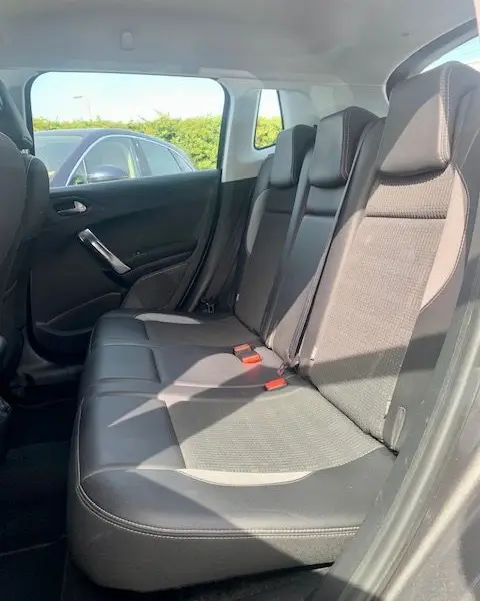 Banquette arrière en cuir noir du Peugeot 2008 gris, vue côté droit avec ceinture de sécurité rouge visible.