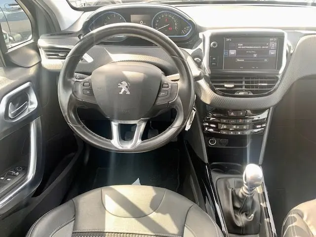 Vue intérieure centrée sur le volant et la console centrale d'une Peugeot 2008 gris foncé, boîte manuelle, 2015.
