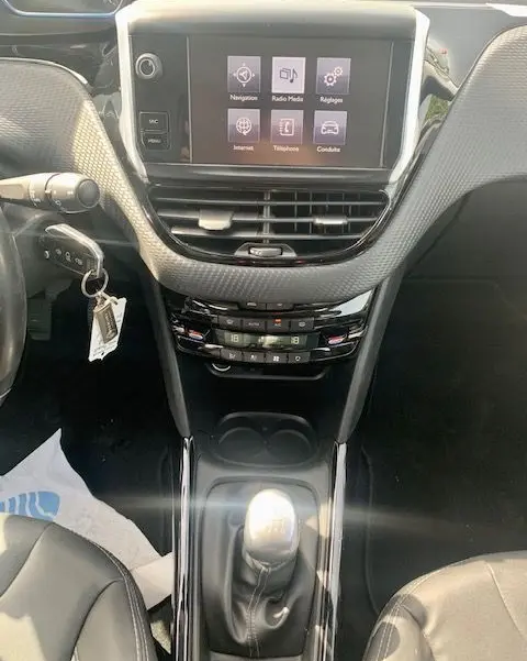 Vue intérieure centrée sur la console centrale du Peugeot 2008 gris, avec écran tactile et levier de vitesse manuel visible.