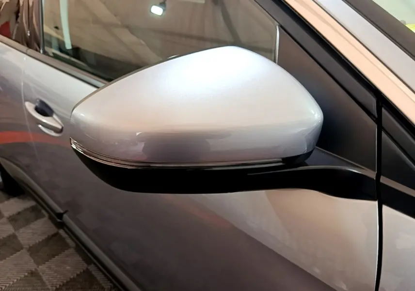 Gros plan sur le rétroviseur électrique gris clair du côté conducteur d’un Peugeot 5008 gris foncé.