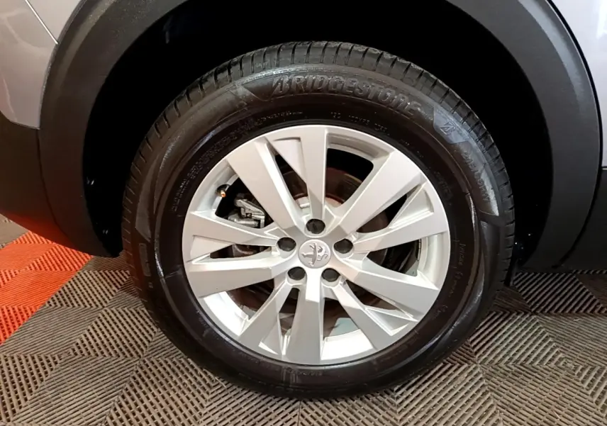 Gros plan sur la roue avant droite du Peugeot 5008 gris foncé avec jante alliage et pneu Bridgestone.