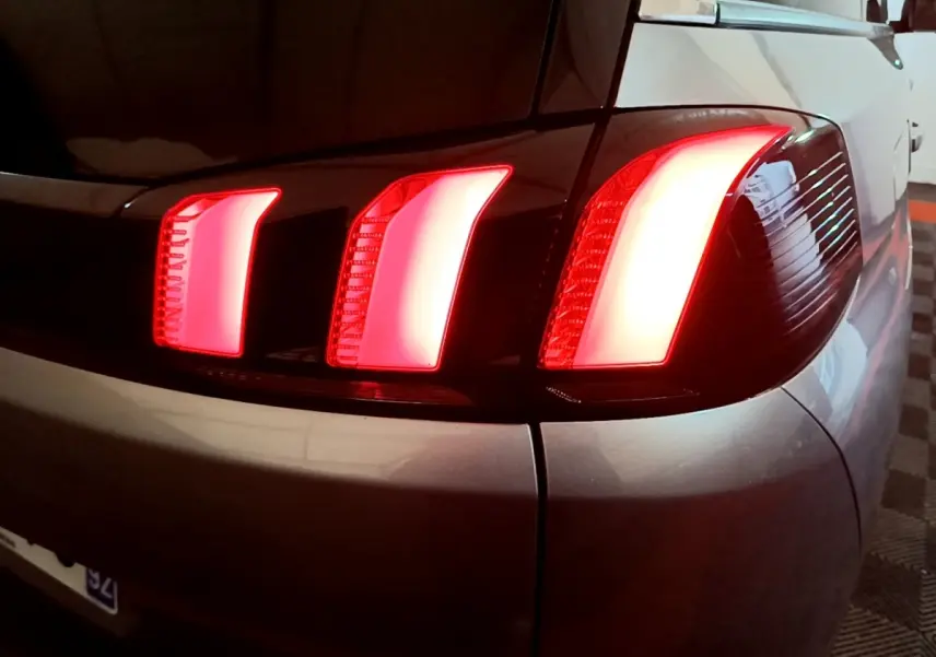 Gros plan sur le feu arrière droit allumé d’un Peugeot 5008 gris foncé, soulignant ses trois griffes lumineuses distinctives.