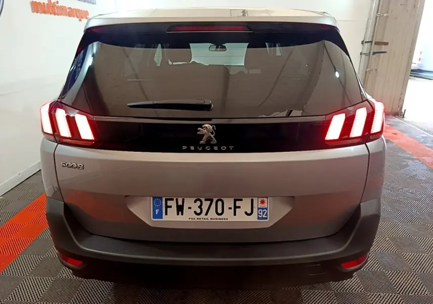 Vue arrière d'un Peugeot 5008 gris foncé avec feux LED allumés dans un garage intérieur.