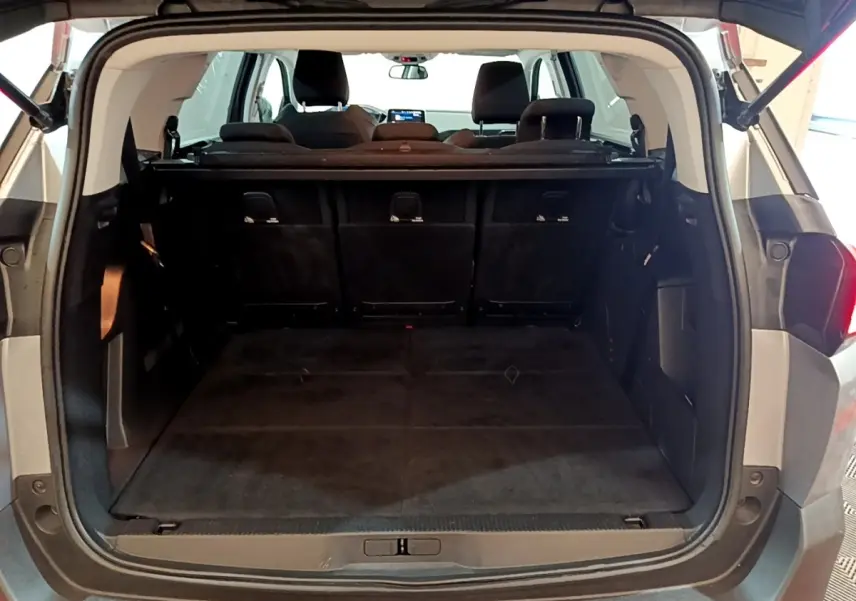 Coffre ouvert vu de l'arrière d'un Peugeot 5008 gris foncé, montrant la banquette arrière et l'espace de chargement.