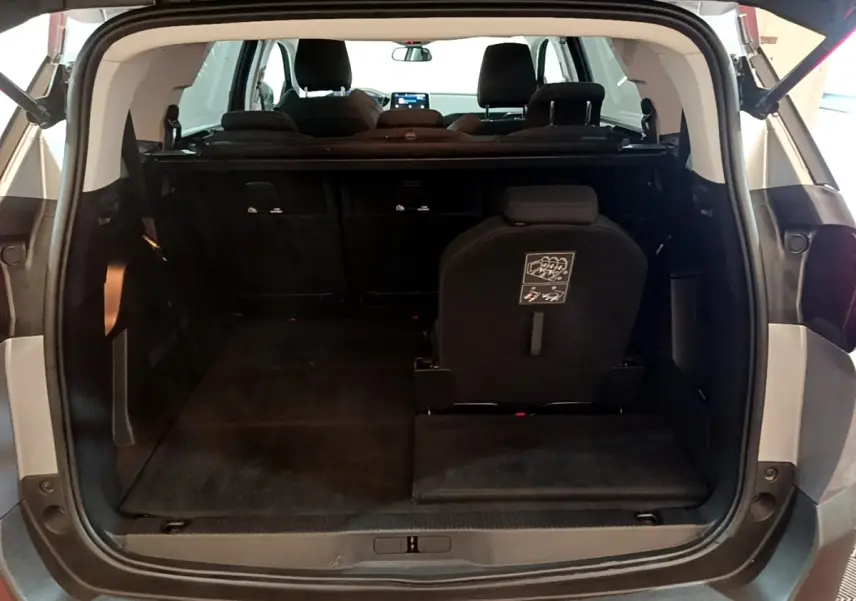 Vue arrière du coffre ouvert du Peugeot 5008 gris foncé, montrant la troisième rangée de sièges rabattables.
