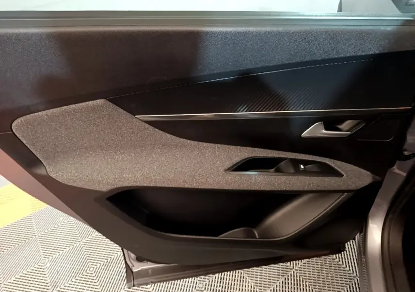 Vue intérieure du panneau de porte côté droit gris foncé du Peugeot 5008 avec insert décoratif noir et commande de vitre.