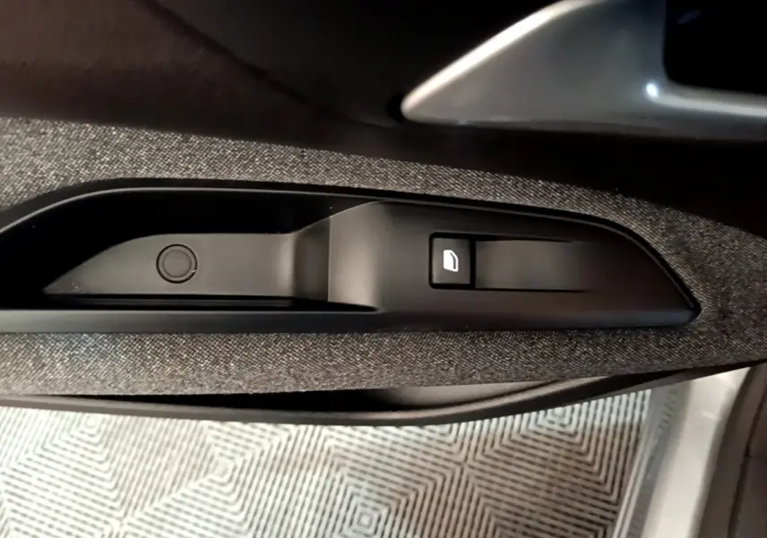 Détail de la poignée intérieure et bouton de verrouillage de porte sur la portière côté conducteur du Peugeot 5008 gris foncé.