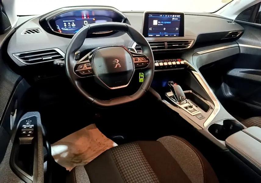 Vue intérieure avant du Peugeot 5008 gris foncé 2020, avec volant cuir compact et écran tactile central.