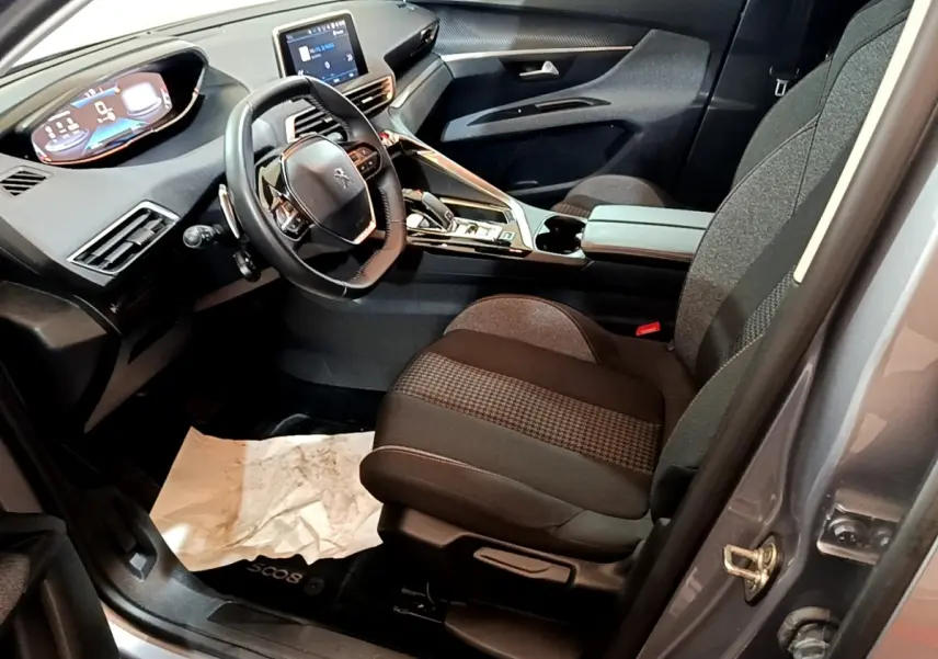 Intérieur avant droit du Peugeot 5008 gris foncé 2020, volant cuir, écran tactile et sièges tissu noirs.
