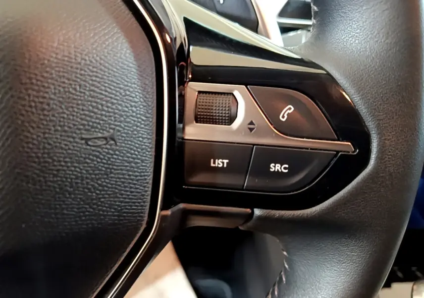 Gros plan sur les commandes gauche du volant cuir noir du Peugeot 5008 gris foncé, boutons LIST, SRC et téléphone.