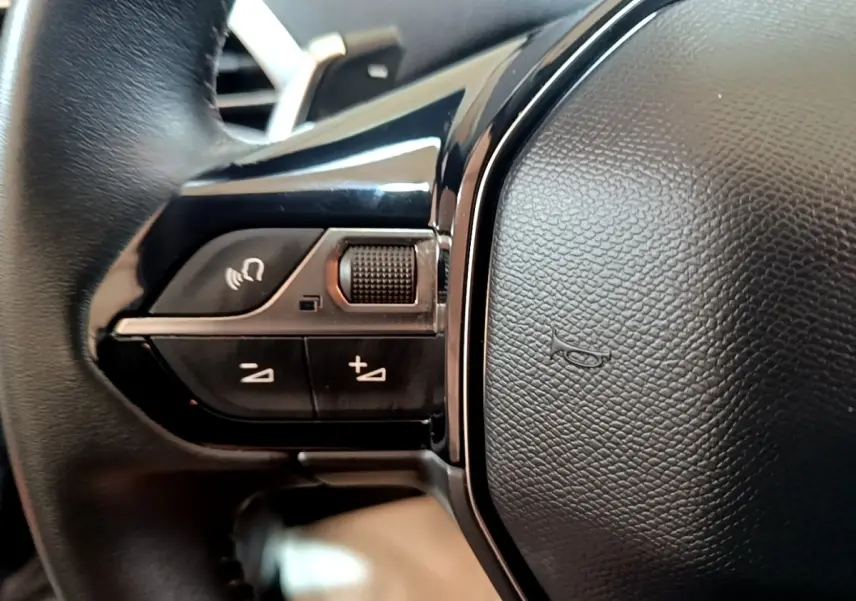 Gros plan sur les commandes gauche du volant cuir noir du Peugeot 5008 gris foncé, version 2020 Active Business.