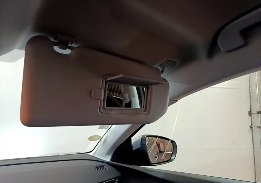 Vue intérieure côté conducteur du pare-soleil avec miroir intégré et rétroviseur extérieur d'un Peugeot 5008 gris foncé.