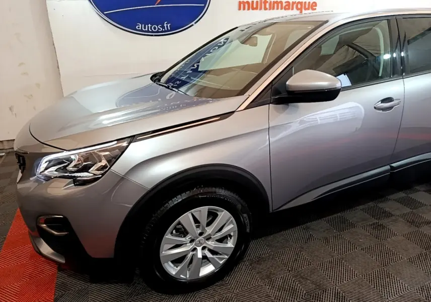 Vue 3/4 avant droit d’un Peugeot 5008 gris foncé avec jantes alliage et rétroviseurs électriques en intérieur showroom.