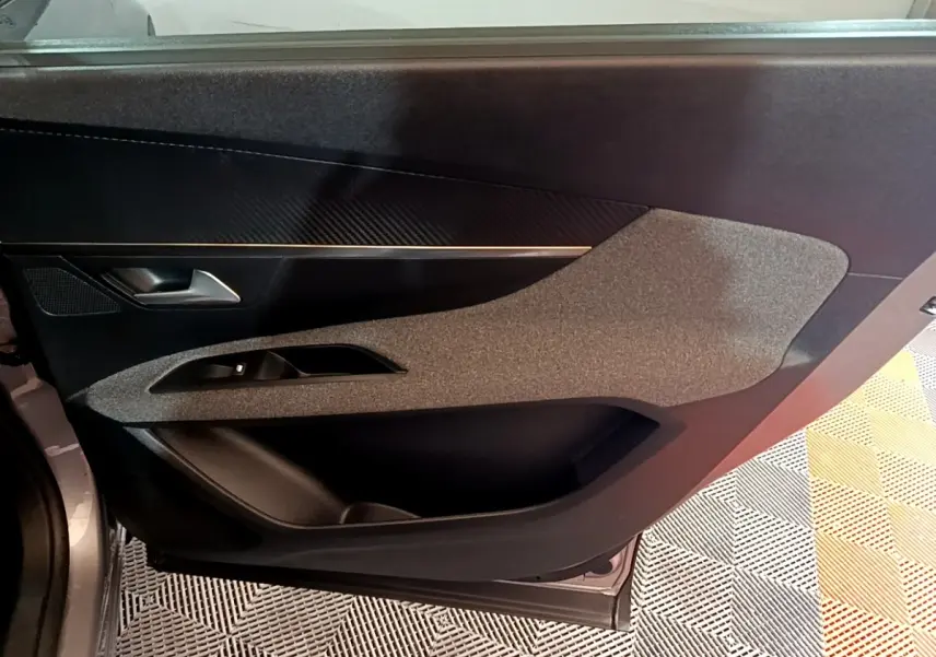 Vue intérieure du panneau de porte côté gauche du Peugeot 5008 gris foncé, avec insert texturé et commande de vitre.