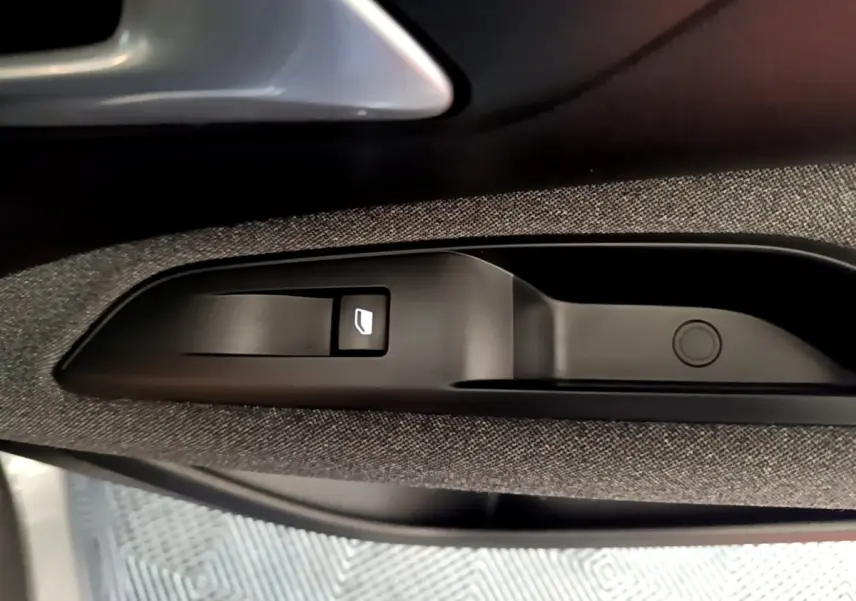 Gros plan sur la commande de lève-vitre côté conducteur du Peugeot 5008 gris foncé, intérieur tissu et plastique.