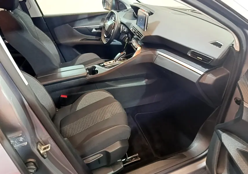 Vue intérieure côté passager du Peugeot 5008 gris foncé, mettant en valeur le tableau de bord moderne avec écran tactile central.