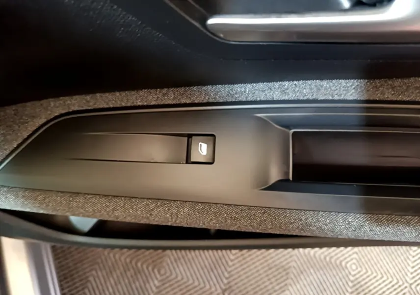 Gros plan sur le bouton de commande de lève-vitre électrique côté conducteur, intérieur tissu gris foncé du Peugeot 5008 2020.