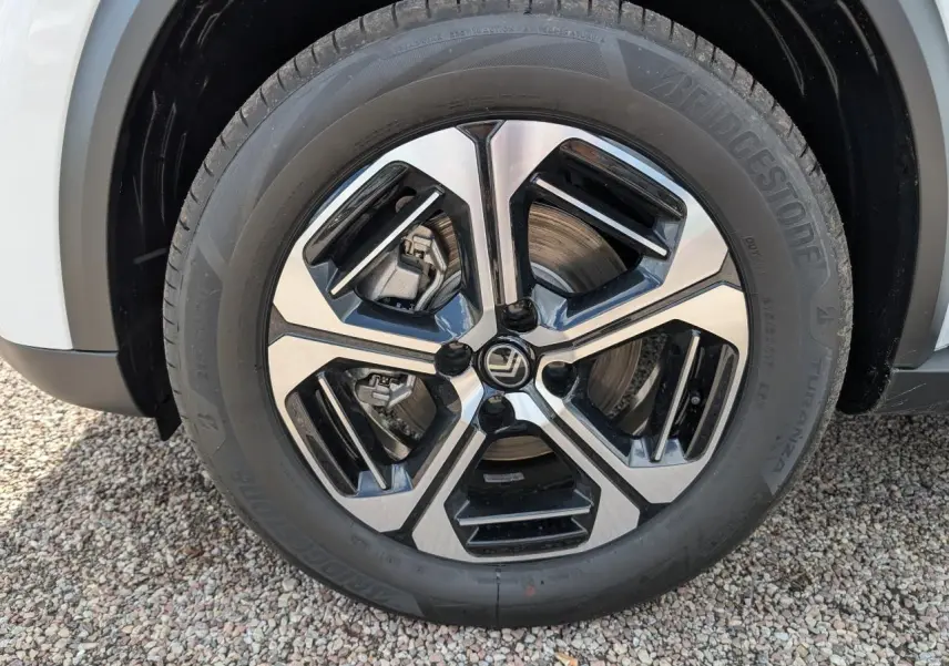 Gros plan sur la jante alliage 17'' diamantée noir et argent d'une Citroën C3 Aircross blanche, partie avant visible.
