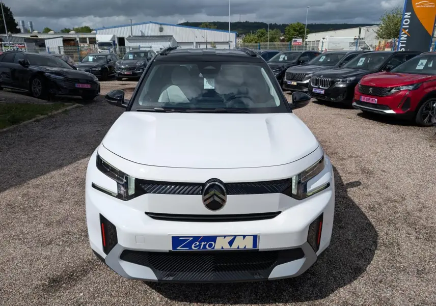 Vue avant d'un Citroën C3 Aircross blanc Banquise avec toit noir et détails noirs brillants sur un parking.