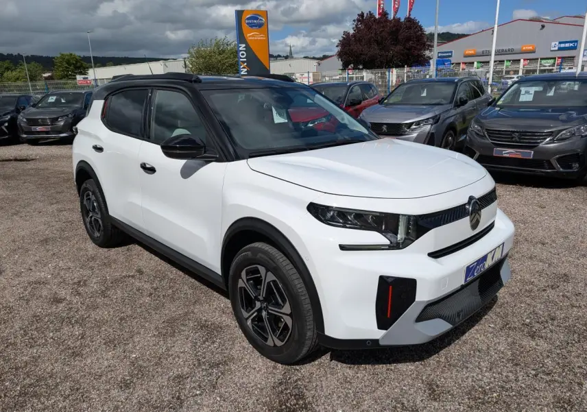 Vue 3/4 avant droite d'un Citroën C3 Aircross blanc avec toit noir et jantes alliage 17'' sur parking extérieur.