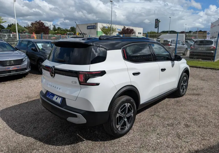 Vue 3/4 arrière droite d'un Citroën C3 Aircross blanc avec toit noir et jantes alliage 17 pouces.