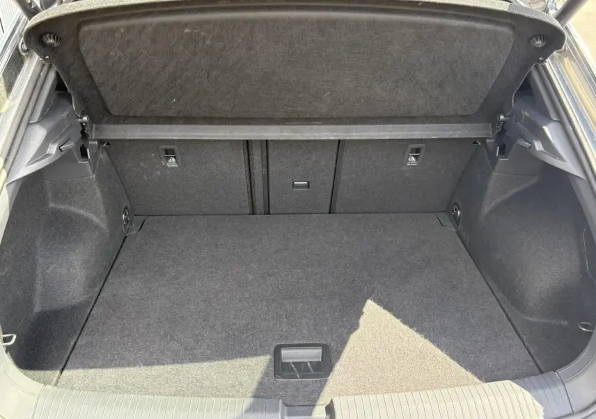 Coffre ouvert du Volkswagen T-Roc gris Indium, montrant un espace de chargement propre et bien agencé.