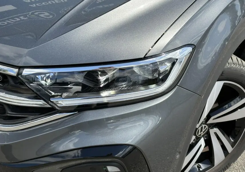 Gros plan sur le phare Matrix LED et la jante alliage 18" du côté avant droit du Volkswagen T-Roc gris Indium.