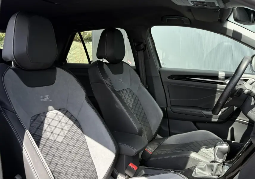 Vue intérieure côté droit montrant les sièges avant cuir et alcantara gris avec logo R-Line brodé sur un Volkswagen T-Roc 2025.