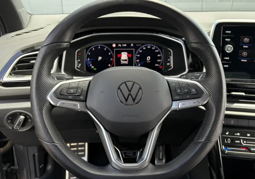 Vue frontale du volant cuir perforé noir avec logo R-Line et tableau de bord digital du Volkswagen T-Roc 2025.
