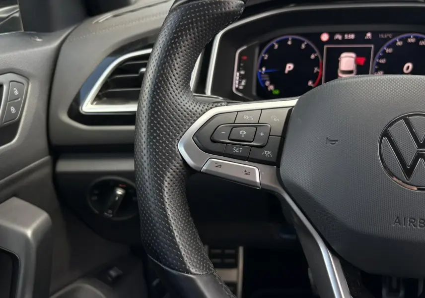 Vue rapprochée du volant cuir perforé avec commandes multifonctions et tableau de bord digital du Volkswagen T-Roc 2025.