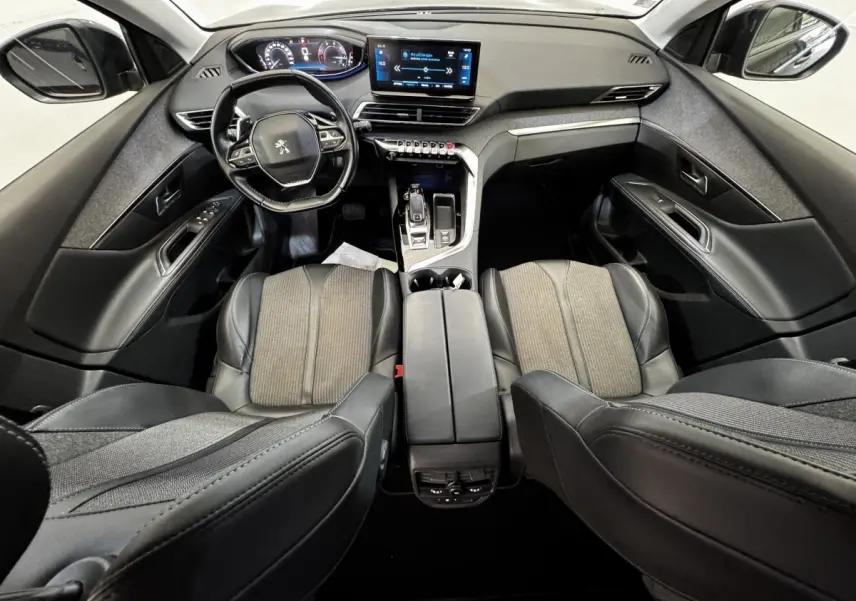 Vue intérieure avant du Peugeot 5008 noir 2022, avec tableau de bord numérique et écran tactile central lumineux.
