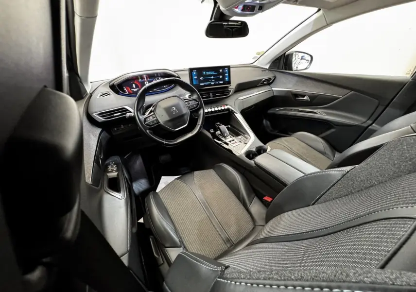 Vue intérieure côté conducteur du Peugeot 5008 noir, mettant en valeur le tableau de bord numérique et l'écran tactile central.