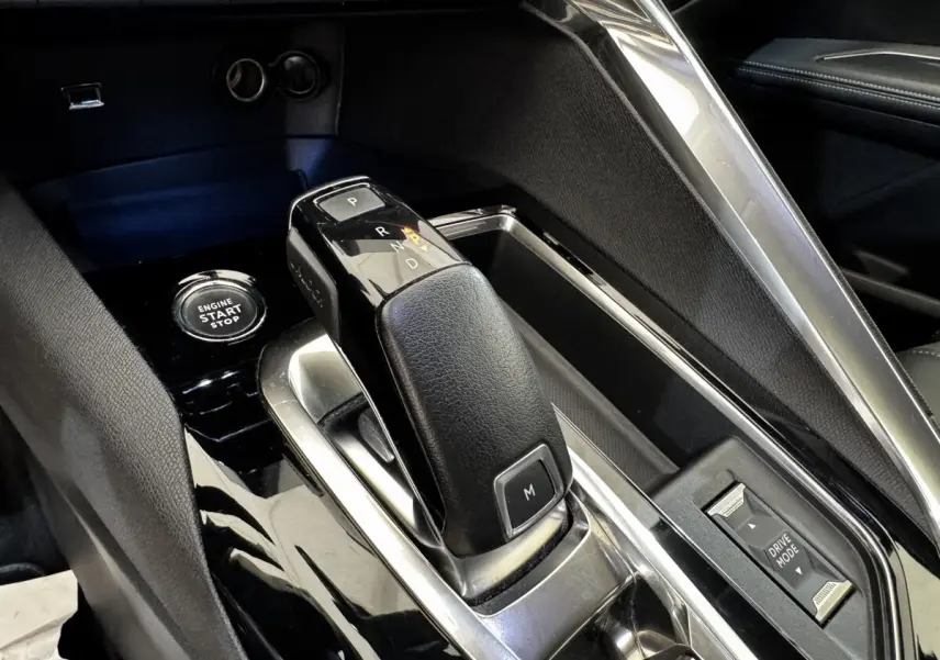 Gros plan sur la console centrale noire du Peugeot 5008 2022, avec levier de boîte auto et bouton start/stop.