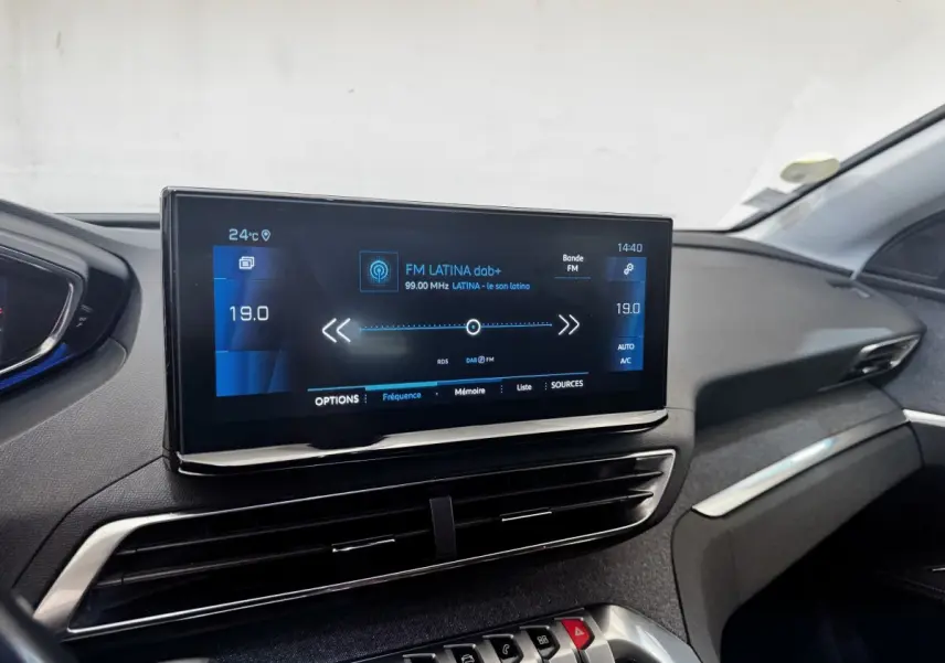 Écran tactile central affichant la radio FM dans l’habitacle noir du Peugeot 5008, vue de face côté passager.