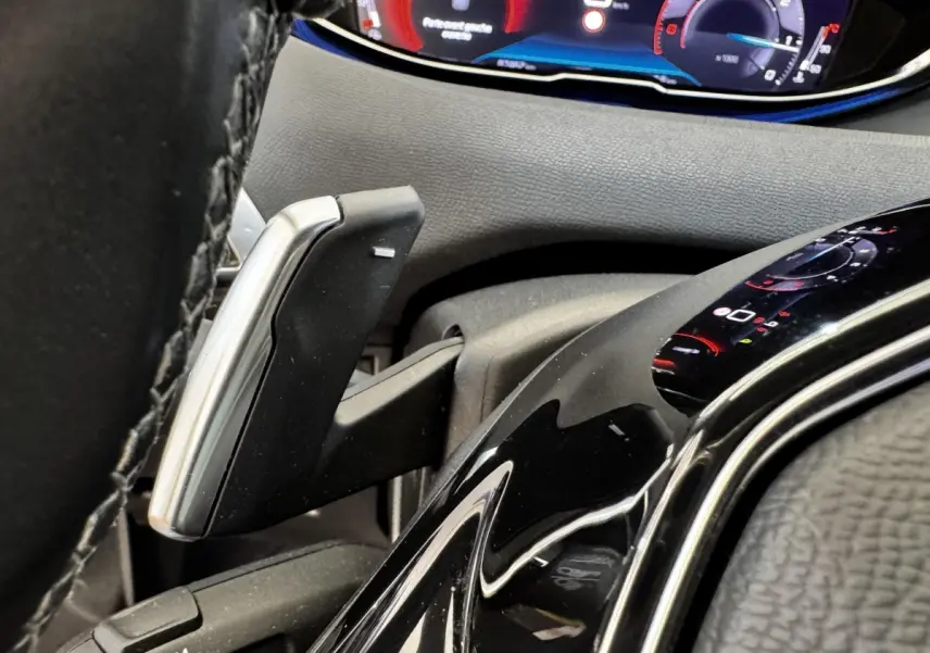 Détail du levier de vitesses et du tableau de bord numérique du Peugeot 5008 noir, vue rapprochée côté conducteur.
