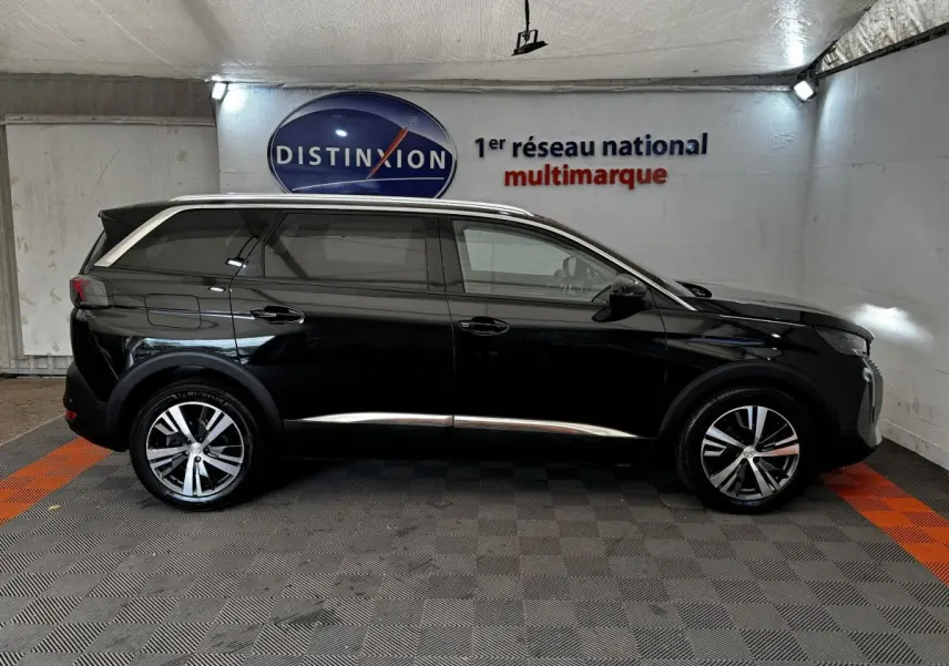 Profil droit d'un Peugeot 5008 noir 2022 avec jantes alliage et vitres teintées dans un showroom.