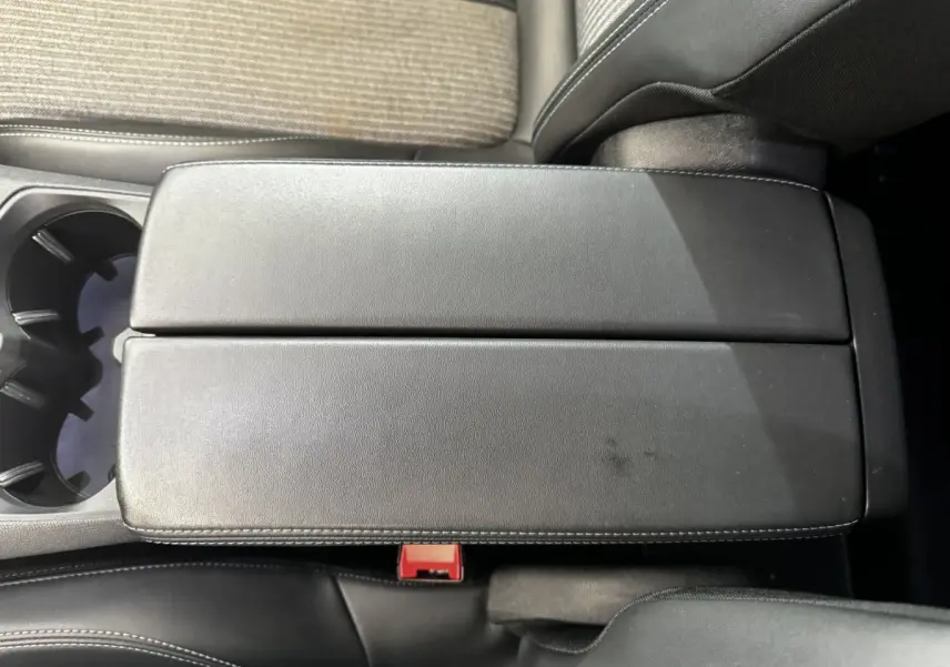 Vue rapprochée du couvercle de la console centrale en cuir noir avec surpiqûres blanches dans l’habitacle d’un Peugeot 5008.