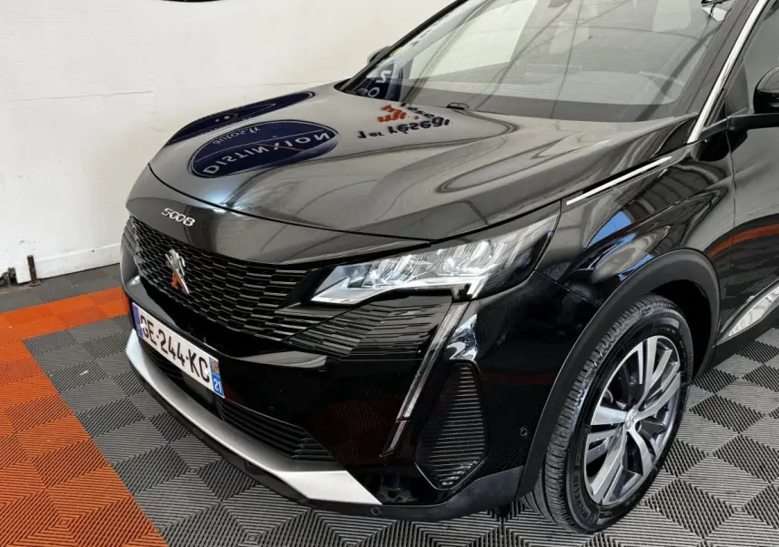 Vue 3/4 avant droit d’un Peugeot 5008 noir 2022 avec calandre noire et phares LED distinctifs.