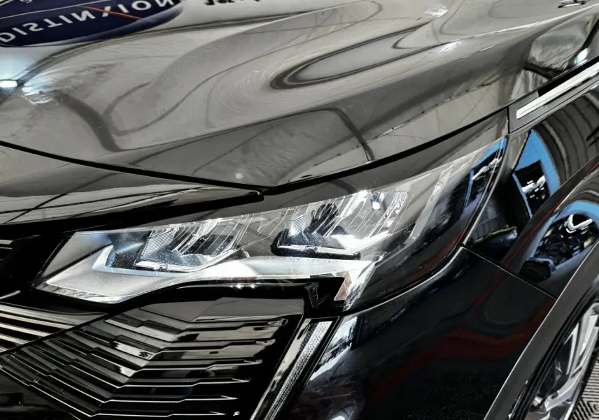 Gros plan sur le phare avant droit du Peugeot 5008 noir 2022, soulignant ses lignes modernes et détails LED.