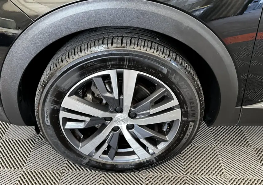 Gros plan sur la roue avant droite noire d’un Peugeot 5008 2022 avec jante alliage bicolore et pneu Michelin.
