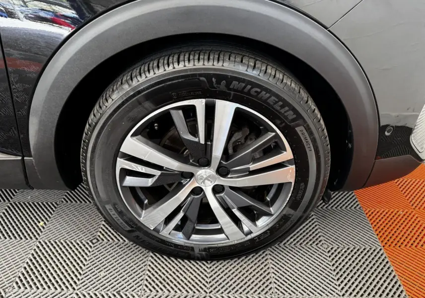 Gros plan sur la roue avant droite noire du Peugeot 5008 2022 avec jante alliage et pneu Michelin.
