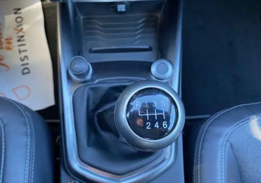 Le levier de vitesses manuel du SSANGYONG TIVOLI 160 e-XDi 2WD Pop gris foncé, vu de dessus entre les sièges avant.