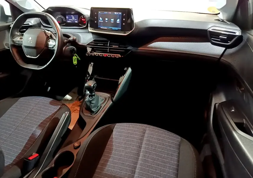 Vue intérieure avant droite du tableau de bord et console centrale de la Peugeot 208 blanche avec écran tactile et boîte manuelle.