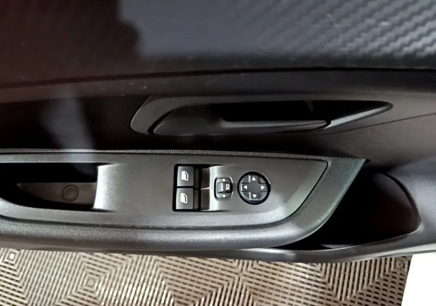 Gros plan sur les commandes de réglage des rétroviseurs et des vitres côté conducteur d'une Peugeot 208 blanche.