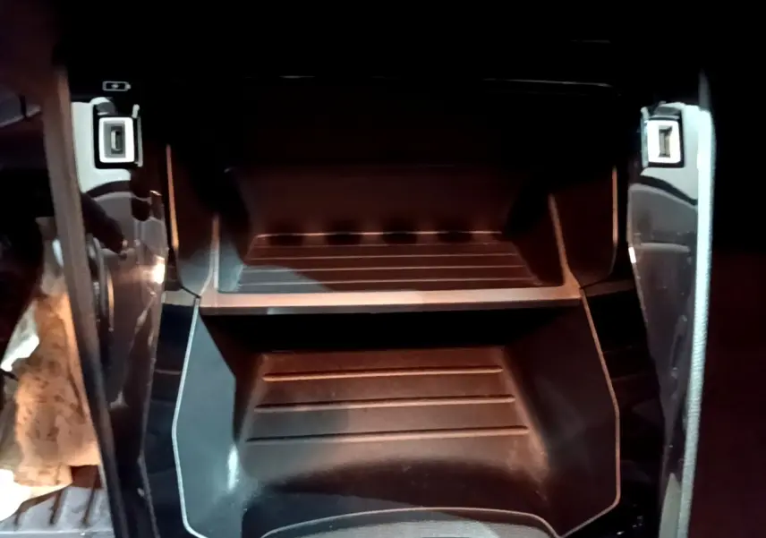 Gros plan sur le rangement central noir de la Peugeot 208 1.5 BlueHDi, montrant un double compartiment vide.