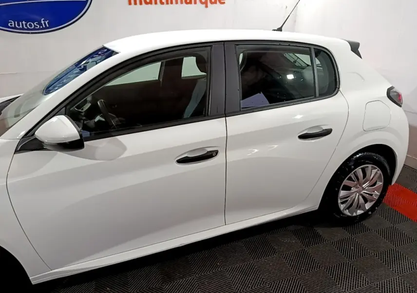 Profil côté gauche d'une Peugeot 208 blanche de 2021, avec jantes alliage et vitres teintées, en intérieur showroom.