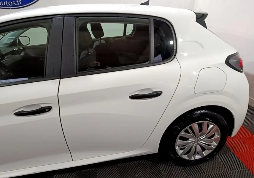 Vue latérale droite d'une Peugeot 208 blanche de 2021, mettant en valeur les poignées noires et les jantes argentées.