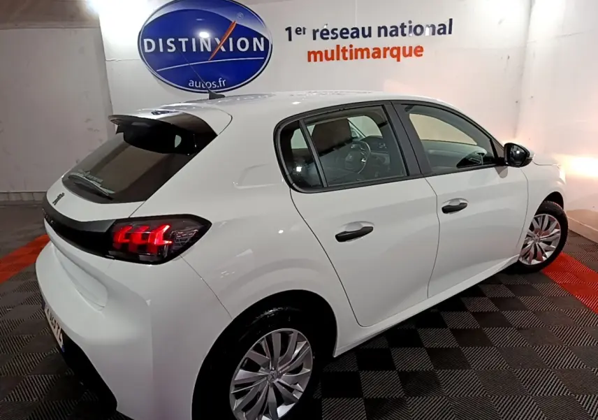 Vue 3/4 arrière droite d'une Peugeot 208 blanche avec feux arrière LED et jantes alliage dans un showroom.